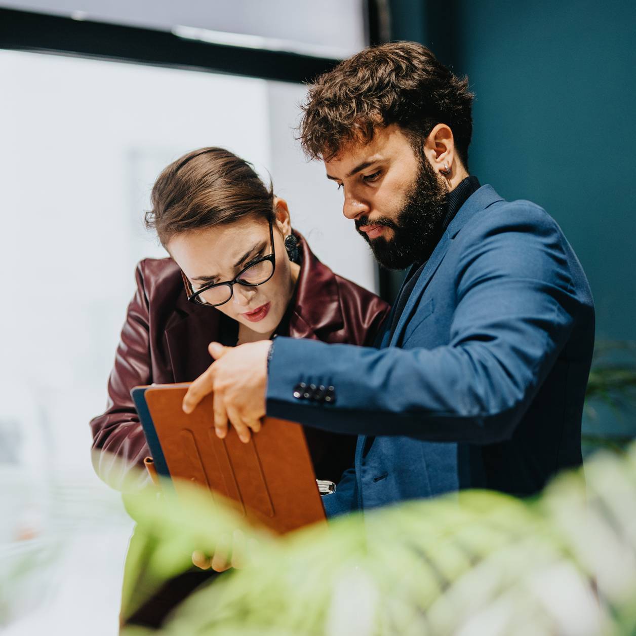 Two business professionals discuss work while using a tablet in an office environment