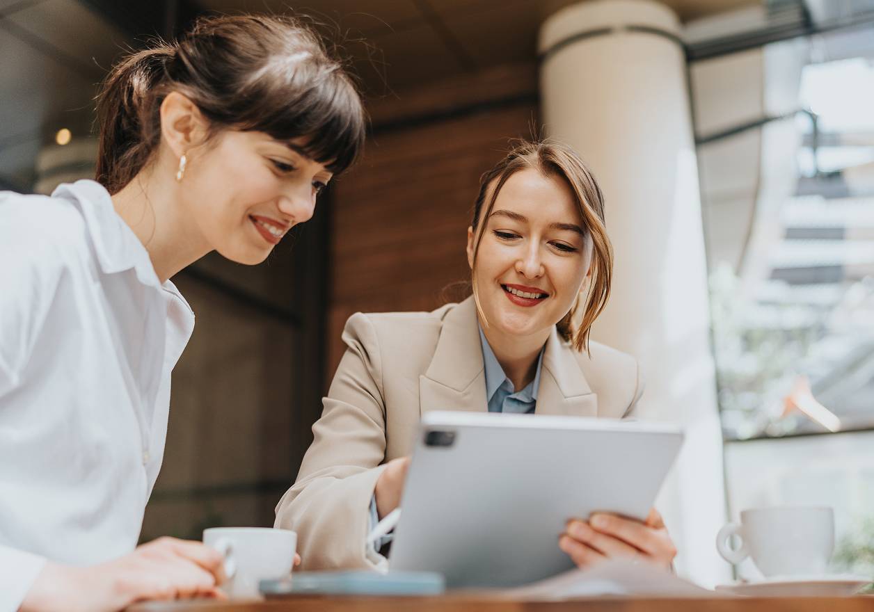 Two women collaborating outdoors with tablet